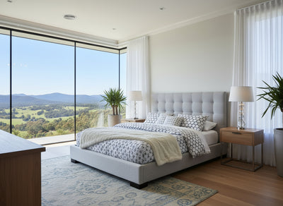 Modern bedroom with a large bed, side tables, and a view of greenery outside.